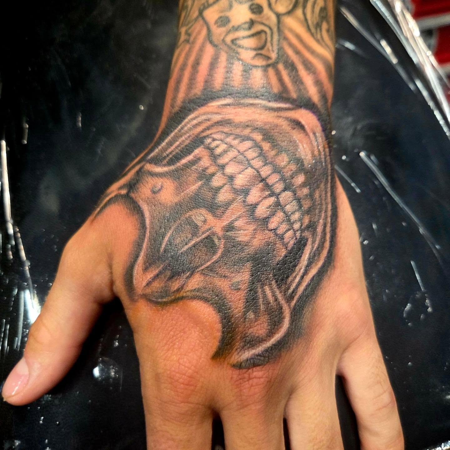 Black and grey anatomical heart and skull motif tattoo on a hand