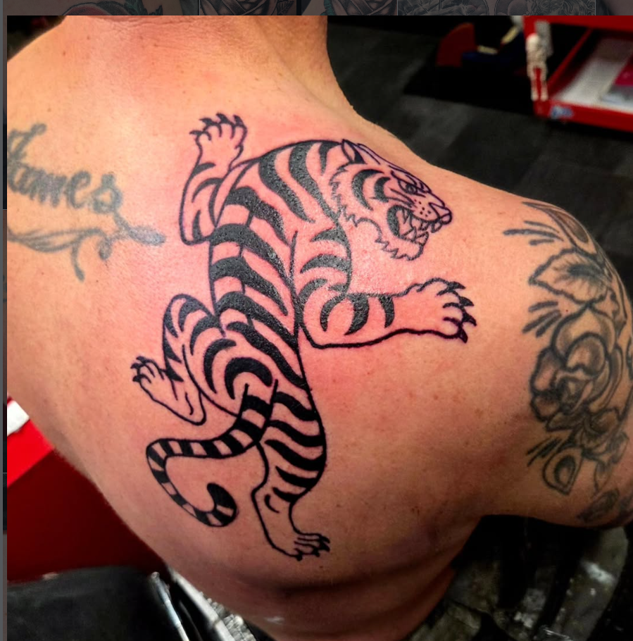 Bold black traditional tiger tattoo across the shoulder blade